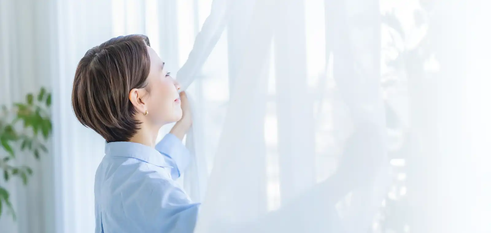 部屋の窓越しに日差しを浴びる人