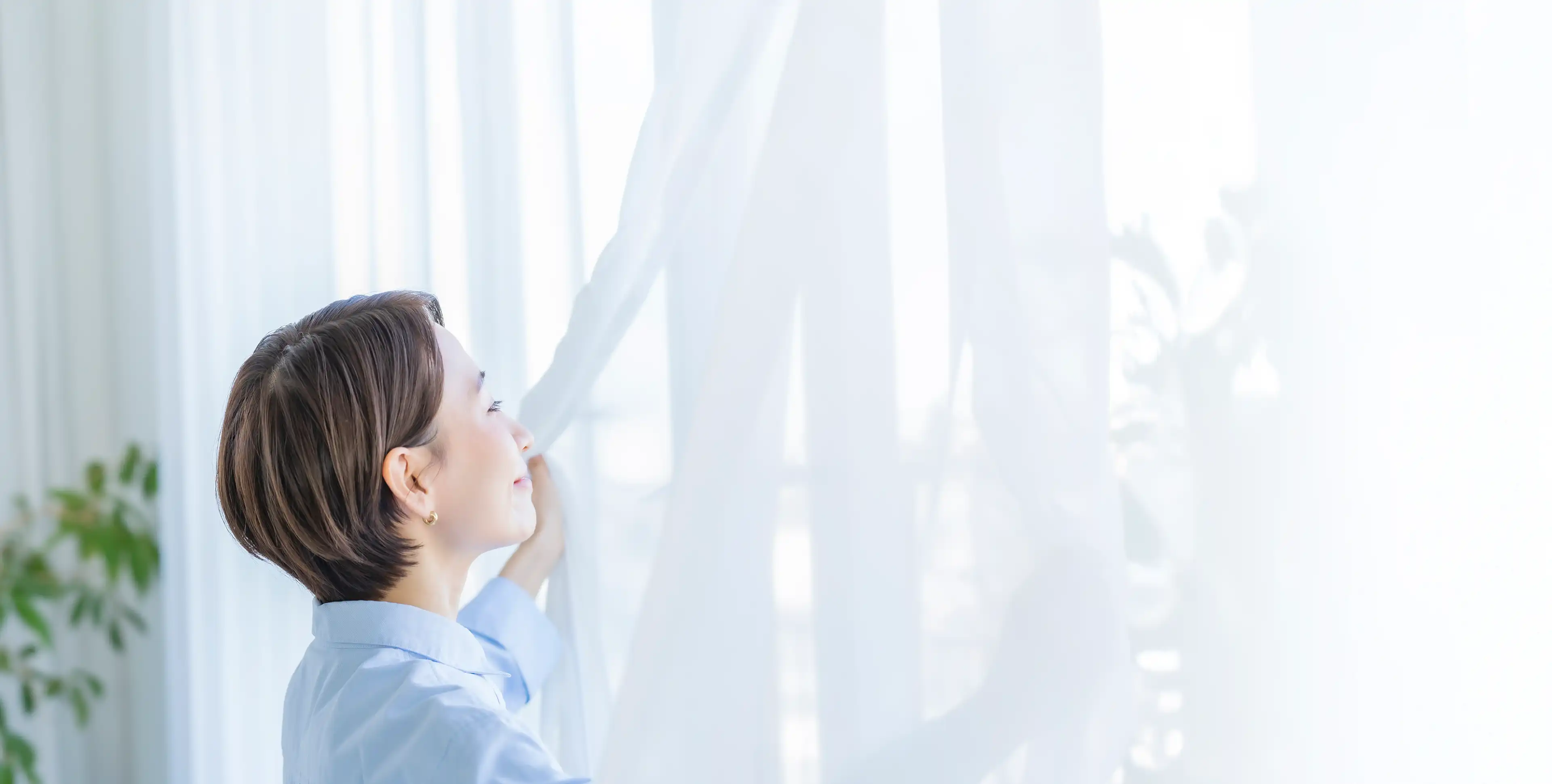 部屋の窓越しに日差しを浴びる人